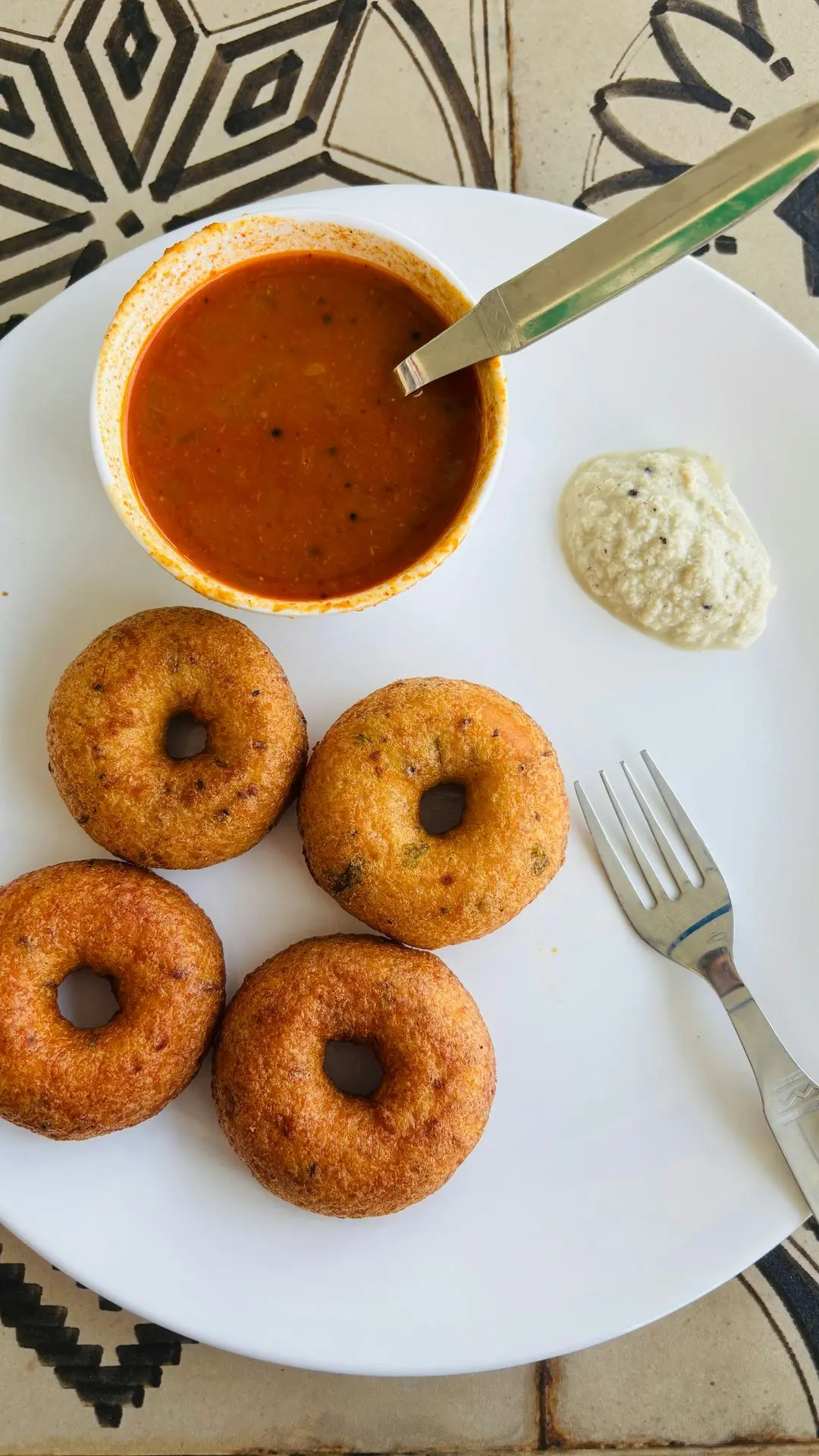 A white plate topped with donuts next to a bowl of sauce